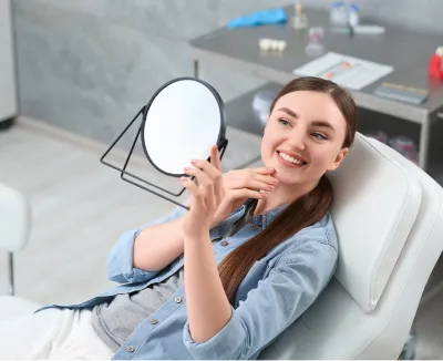 Image of a smiling woman in a chair holding a mirror